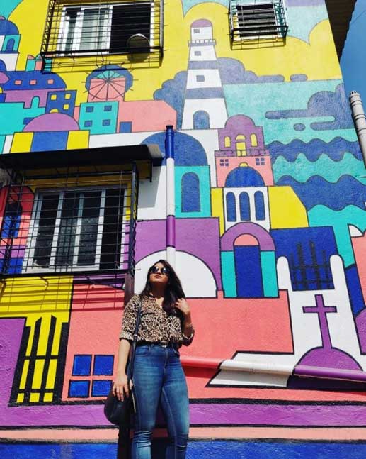 visitor posing in front of street art in mumbai at tribe girls hostel vile parle